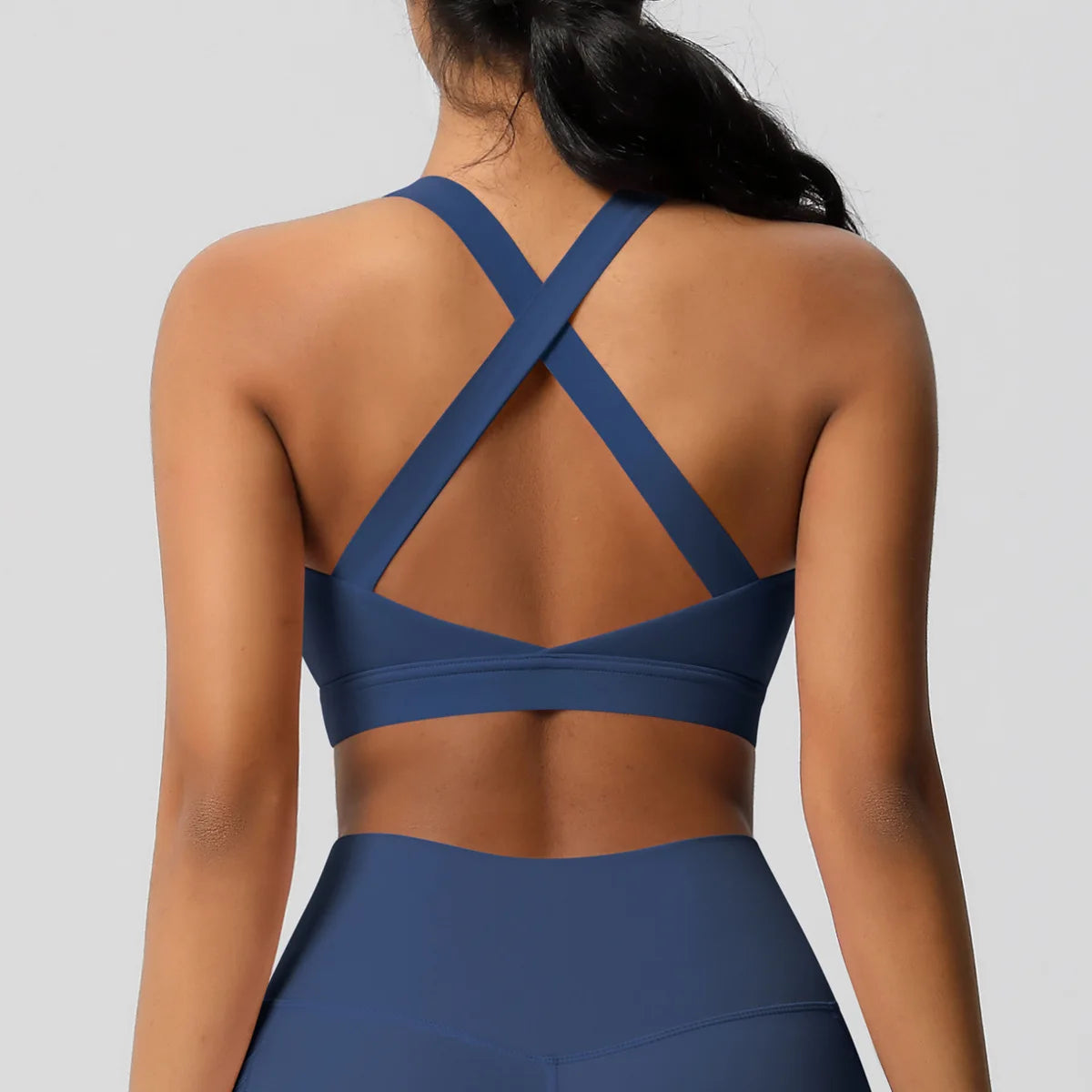 Blue sports bra with criss-cross back design on a plain background