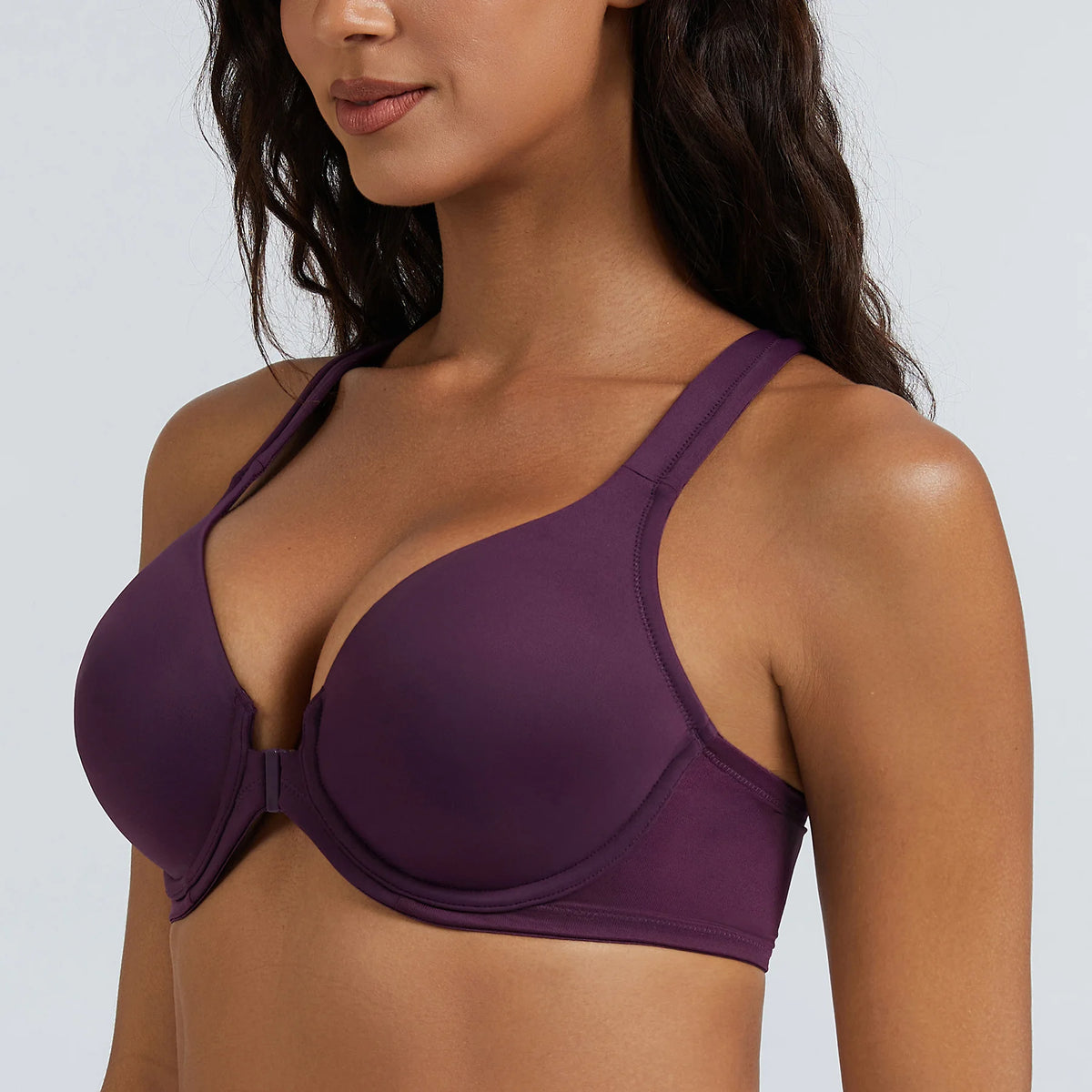Woman wearing a purple bra against a plain background