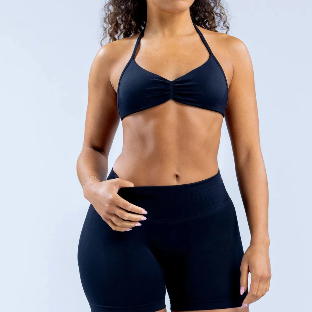 Person wearing a black sports bra and shorts on a light gray background