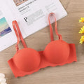 An orange textured wireless bra laid flat on a light wood surface, with an open magazine underneath and small yellow flowers at the edges.
