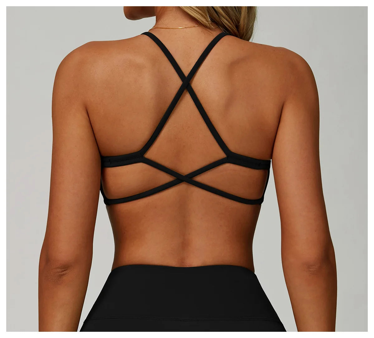Black strappy top worn by a person on a plain background