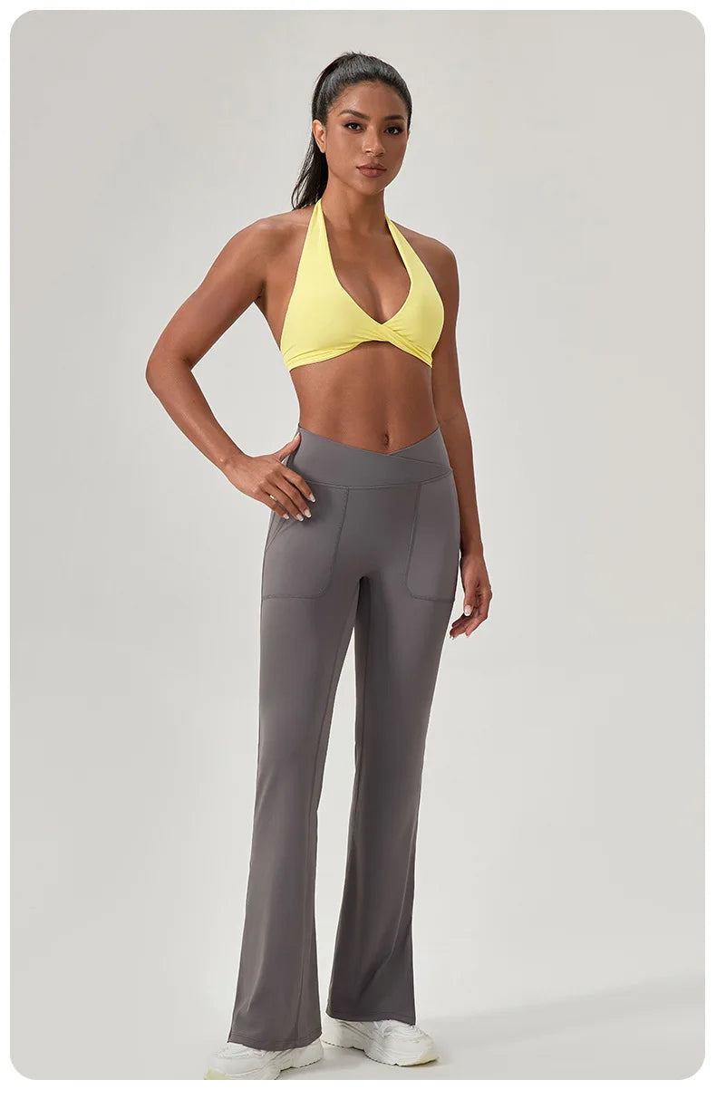 Woman wearing a yellow sports bra and gray leggings on a light gray background