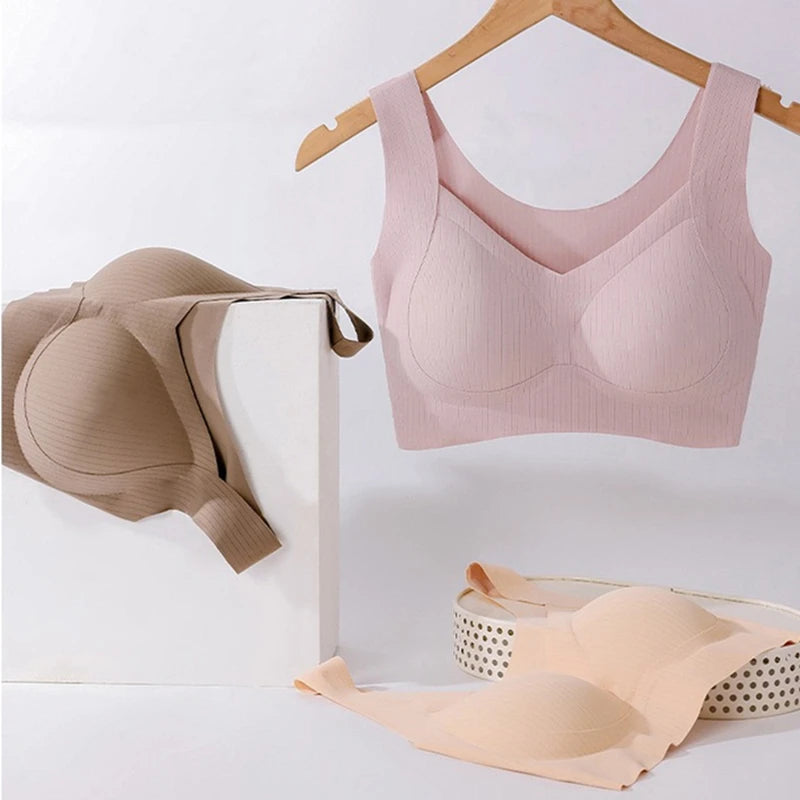 Pink bra on a hanger with beige bras on a white surface