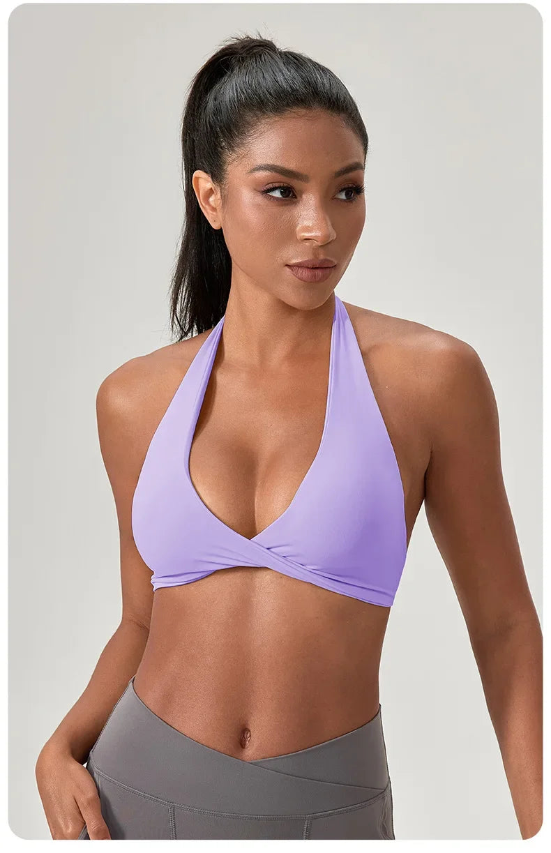 Woman wearing a purple sports bra and gray leggings on a plain background