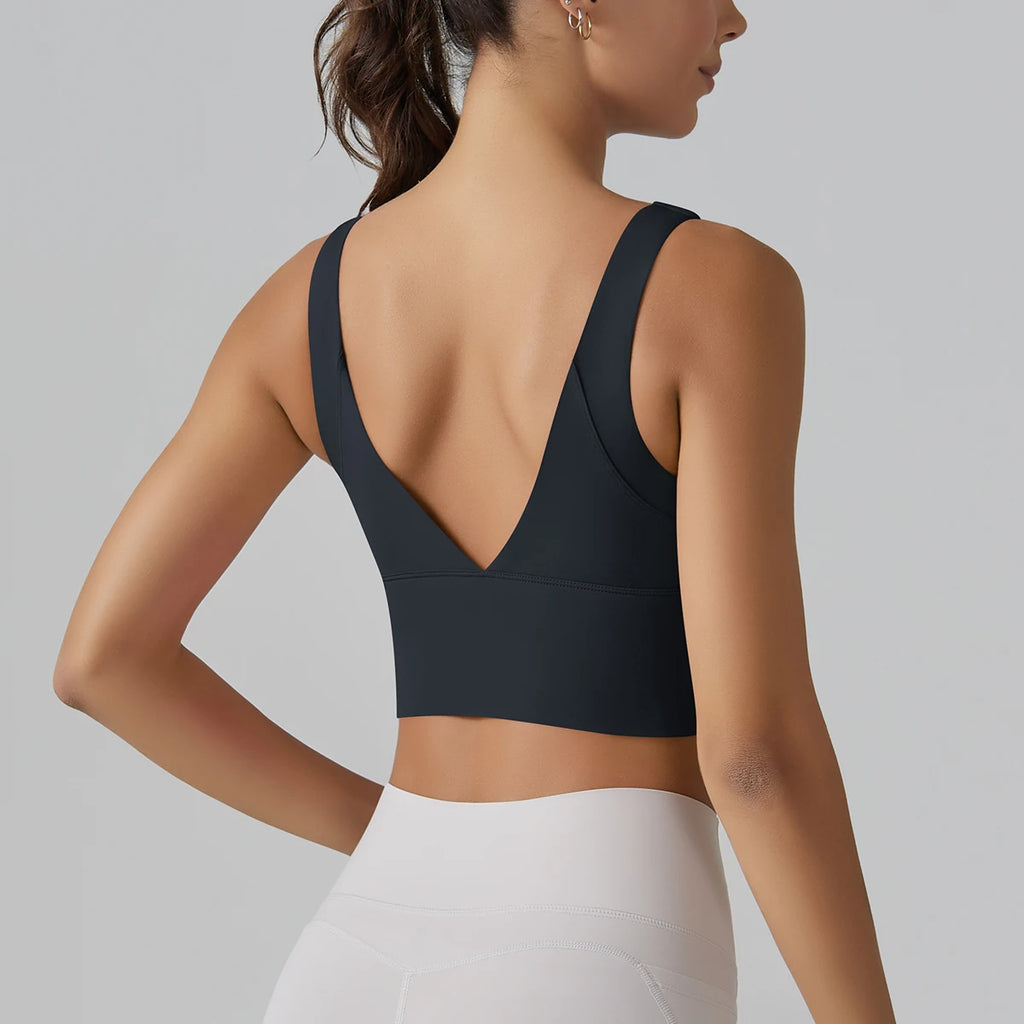 Person wearing a black sports bra and white leggings on a gray background