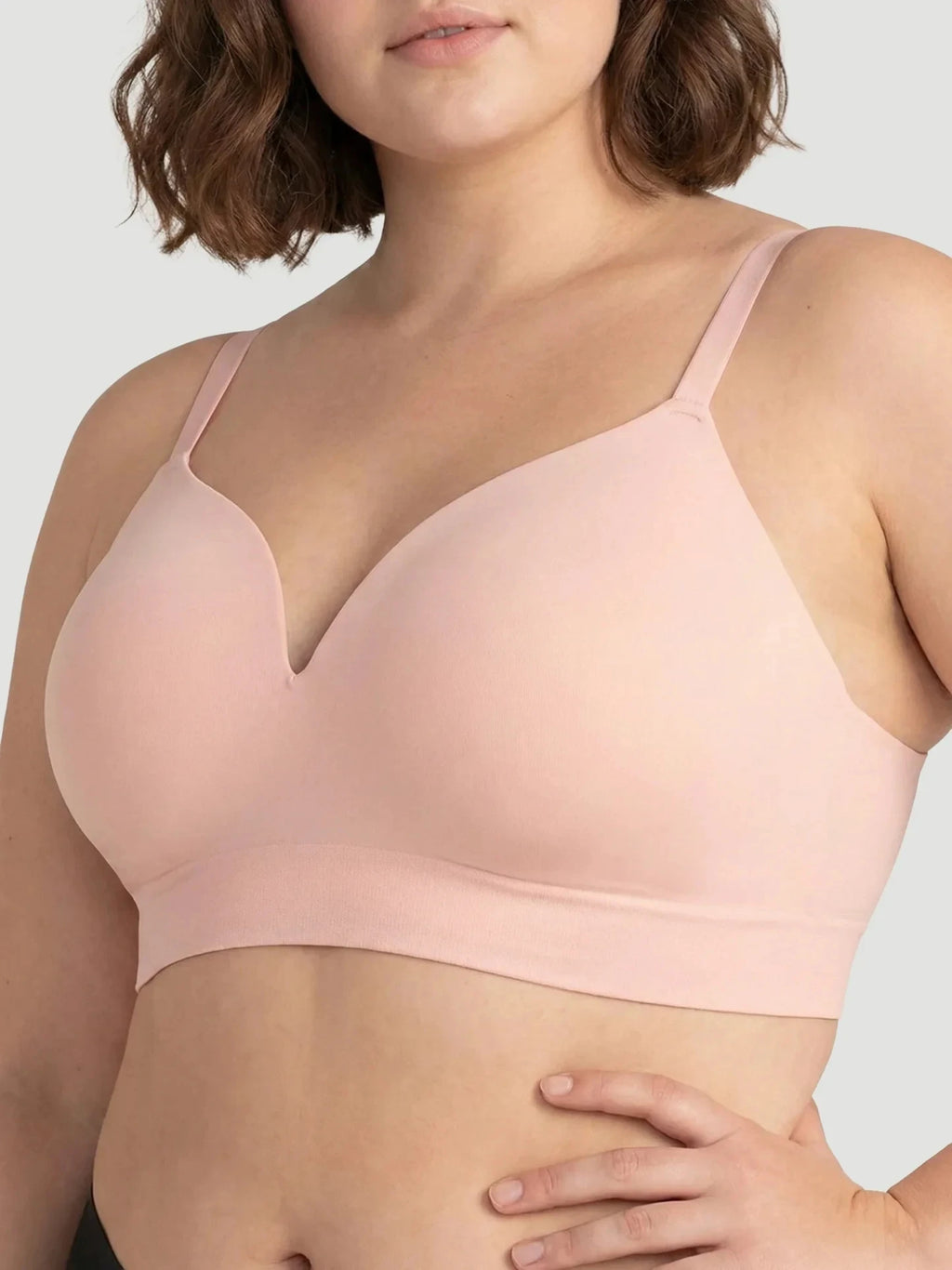 Woman wearing a light pink bra against a neutral background