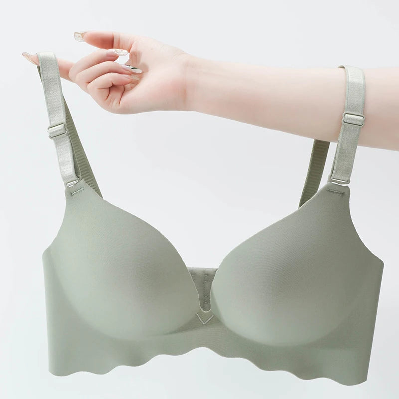 Light gray bra held up by a hand on a light gray background