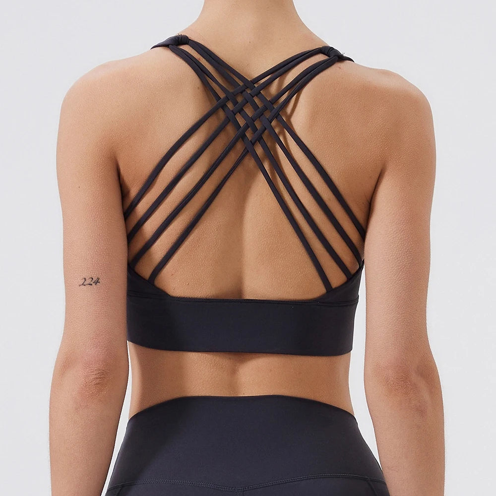 Black sports bra with criss-cross straps on a plain background