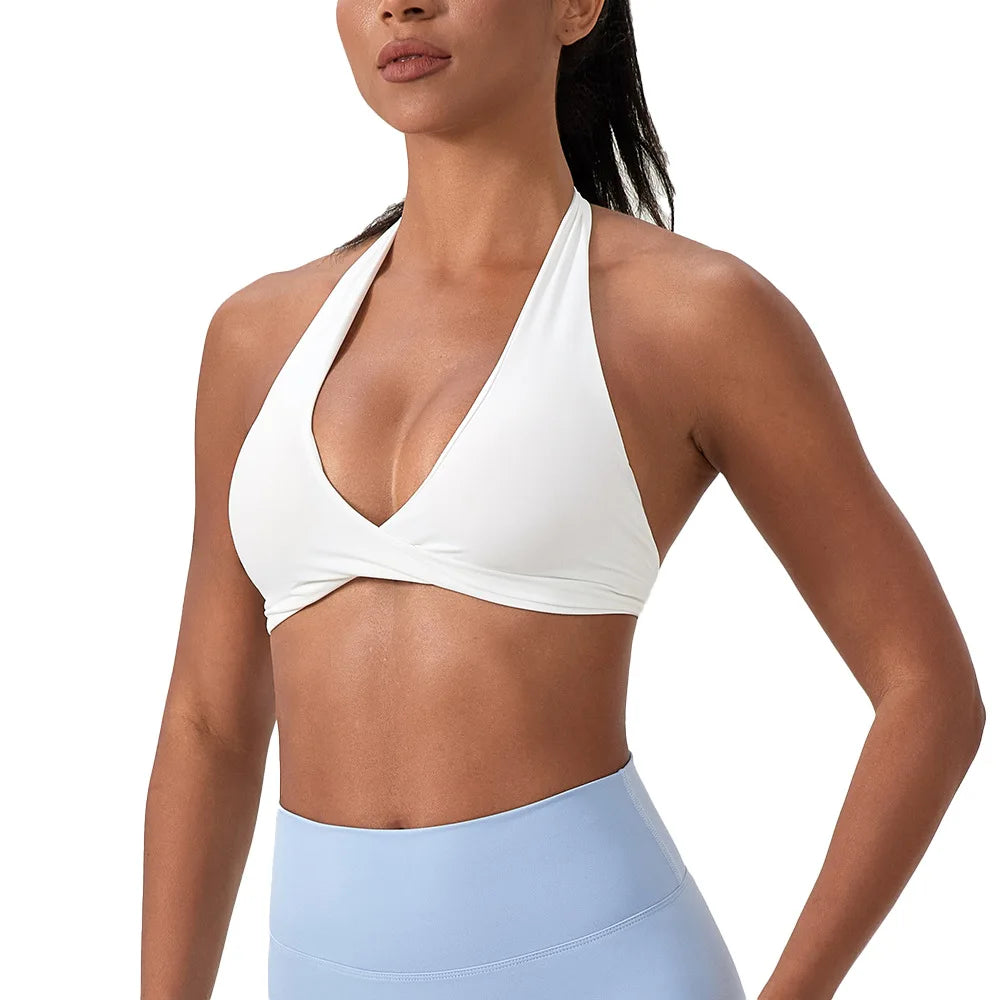Woman wearing a white sports bra and light blue leggings on a white background