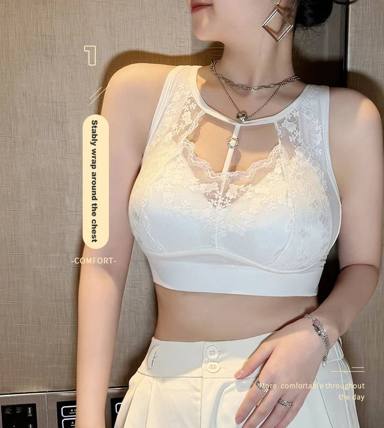 A woman wearing a white wireless bralette with floral lace cups and a keyhole front detail, paired with matching white bottoms. The photo is cropped from the lower face to the hips against an indoor wall background, with small text callouts near the garment.