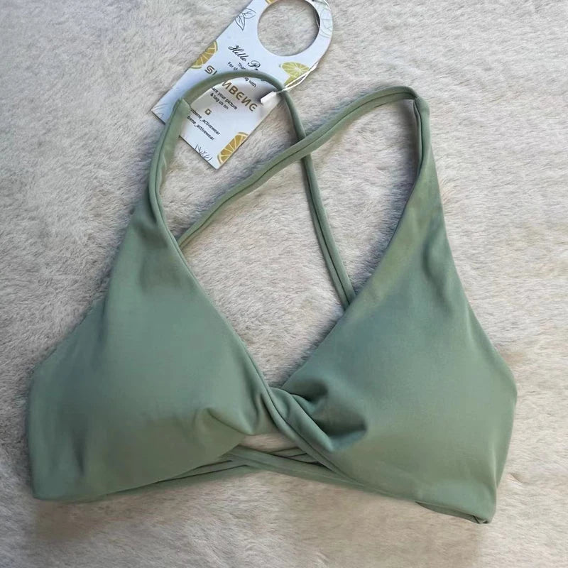 Green bikini top on a beige surface with a tag attached