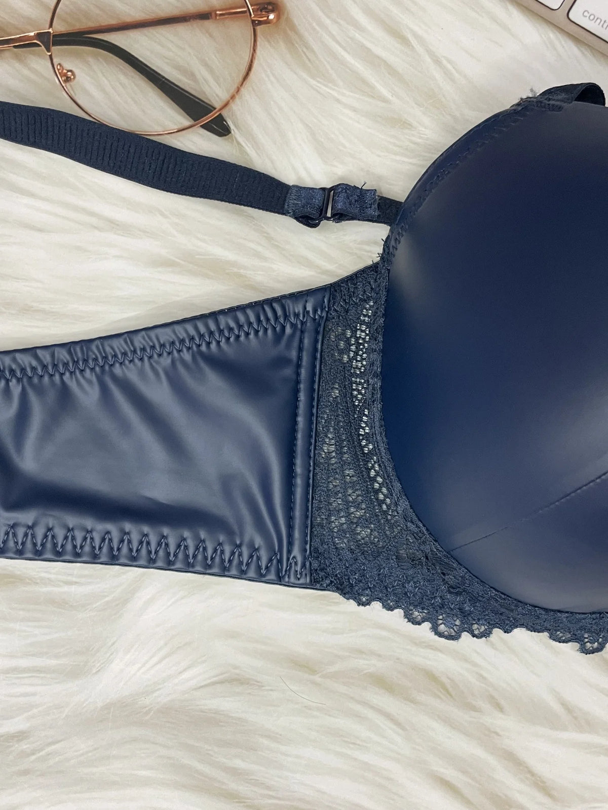 Navy blue bra on a white textured surface with glasses in the background