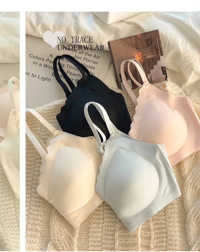 Four wireless underwire bras in black, cream, pale blue, and blush pink, arranged on a textured beige knit blanket with printed paper props.