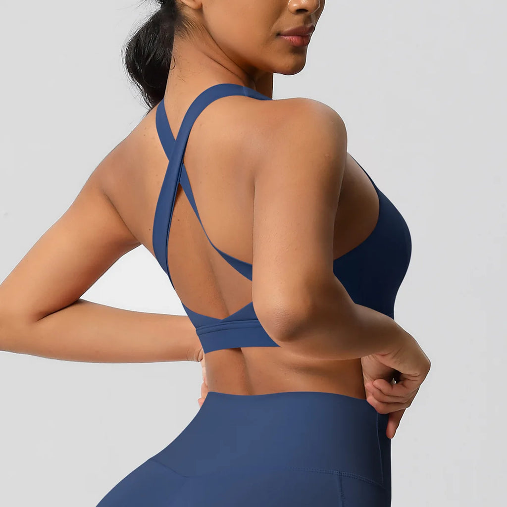 Woman wearing a blue sports bra and leggings on a gray background