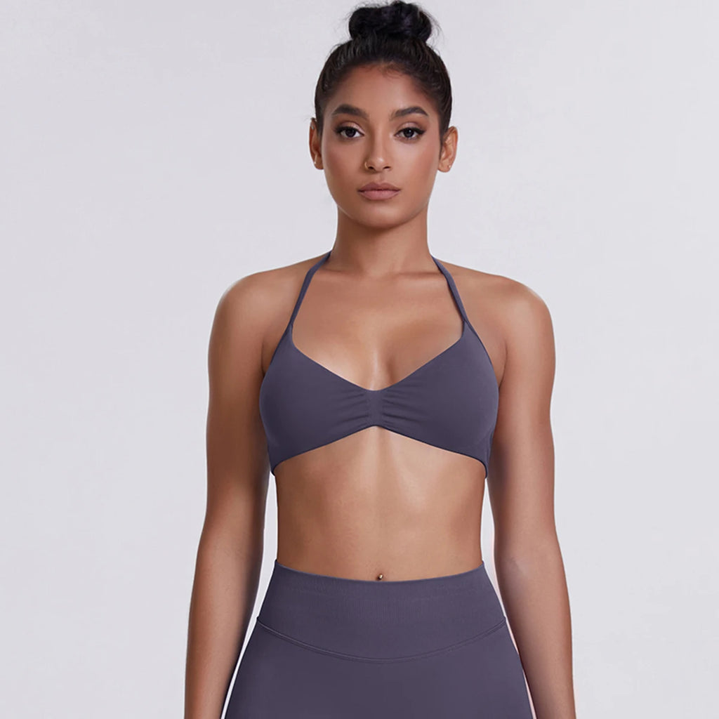 Woman wearing a purple sports bra and leggings on a white background