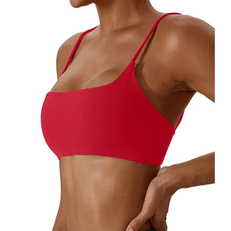 A close-up of a woman wearing a bright red scoop-neck sports bra against a plain white background.