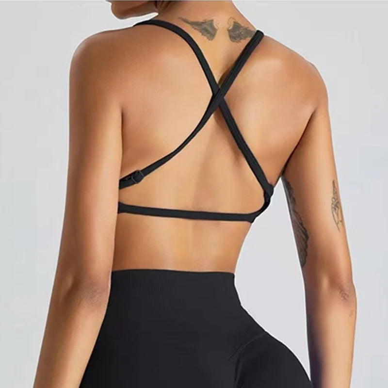 Person wearing a black strappy top against a light gray background