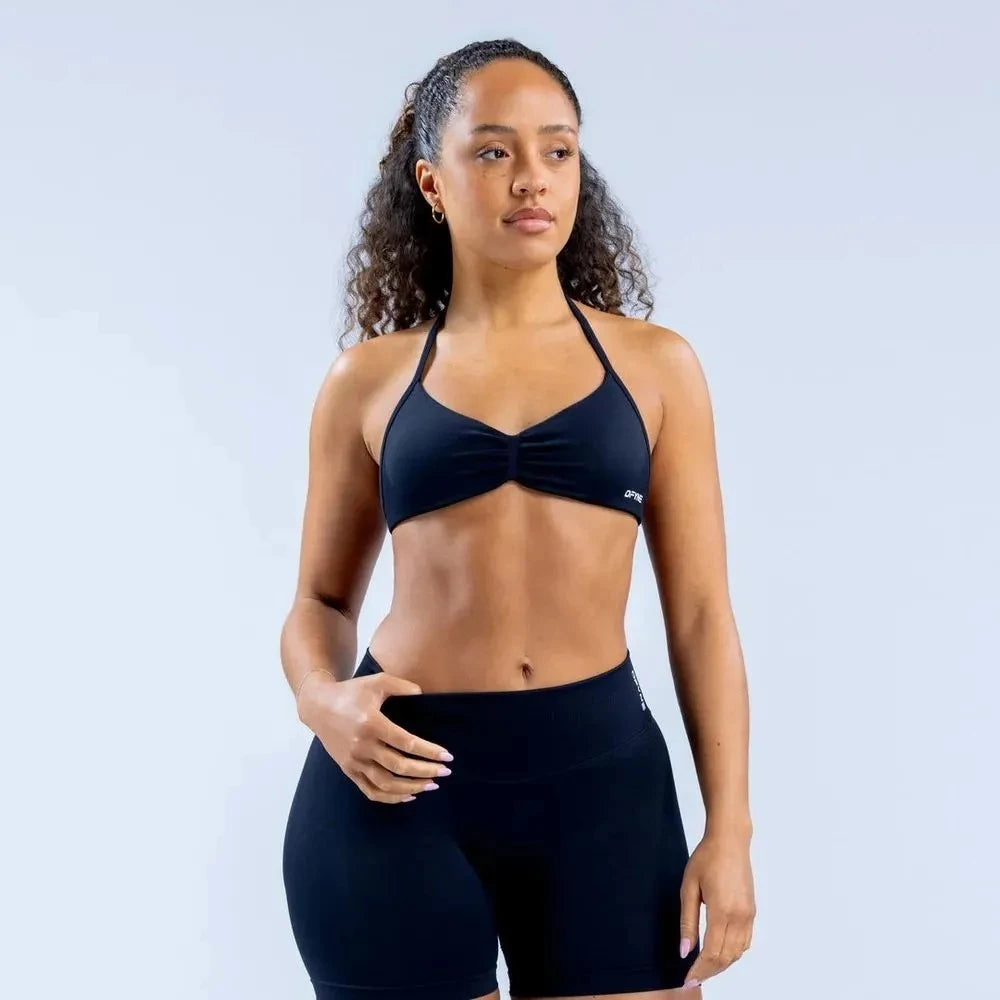 Woman wearing a black sports bra and shorts on a light gray background