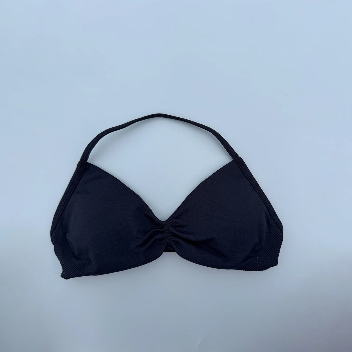 Black bikini top on a light blue background