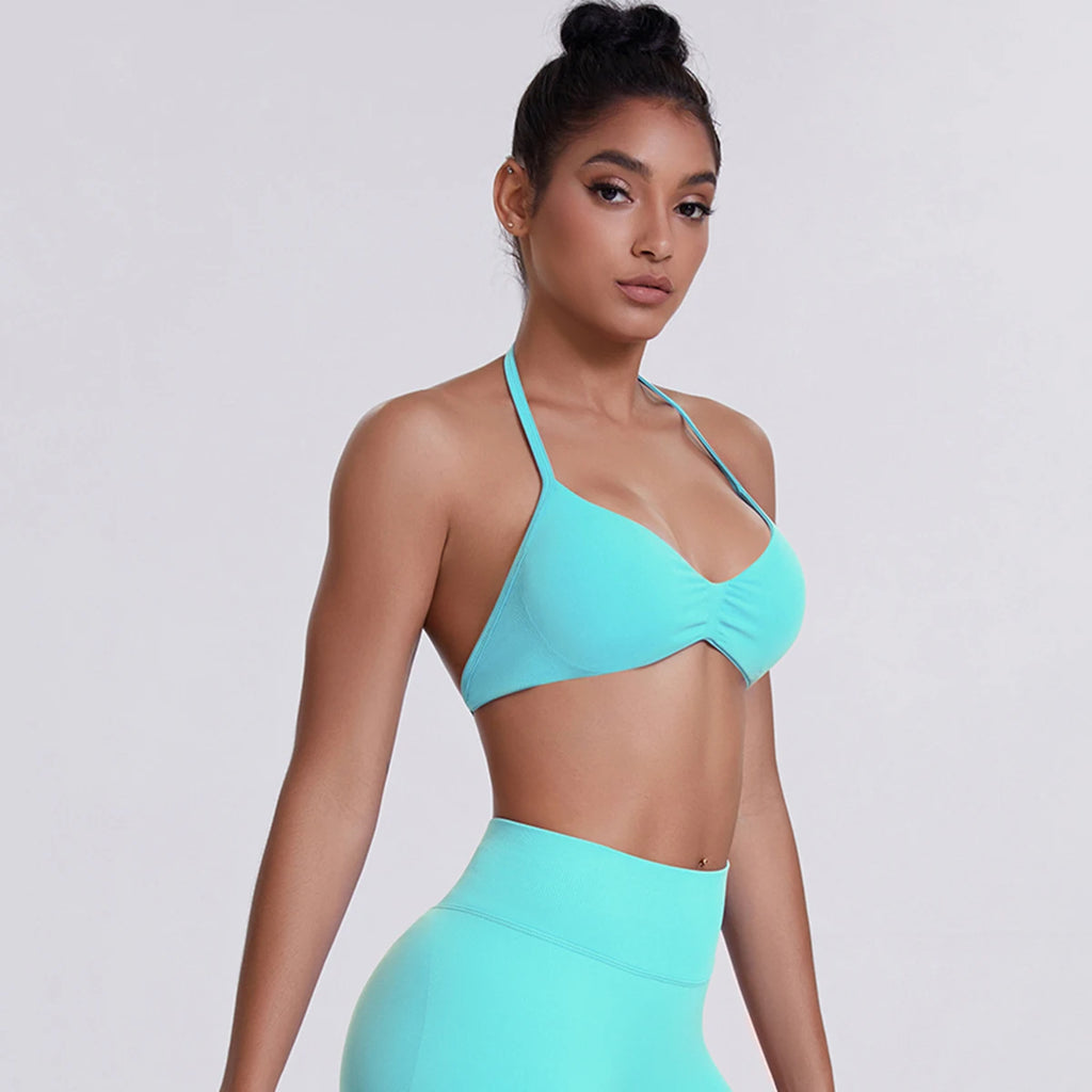 Woman wearing a turquoise sports bra and leggings on a light gray background