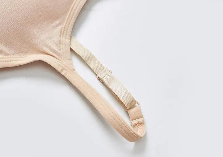 Close-up of a beige bra strap and adjustment buckle on a light gray background.
