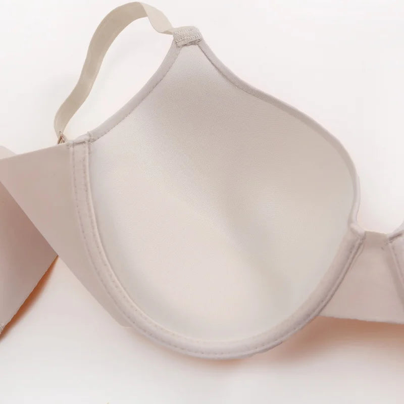 A close-up of a seamless light beige underwire bra cup and band, showing the smooth fabric texture and elasticized edge on a white background.