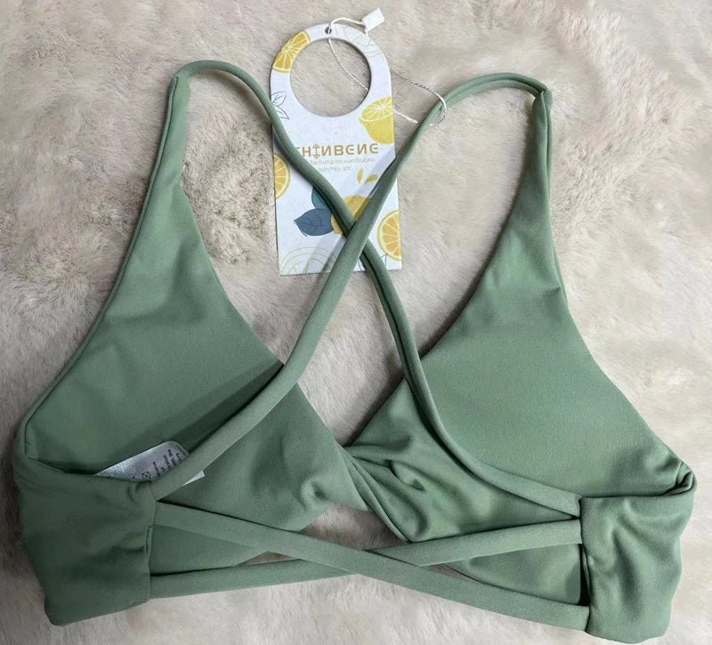 Green bikini top with a tag on a beige surface