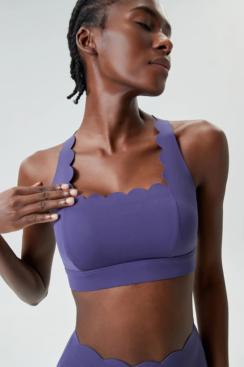 Woman wearing a purple sports bra and leggings against a plain background