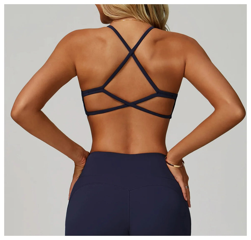 Person wearing a black strappy top and dark blue pants on a light gray background