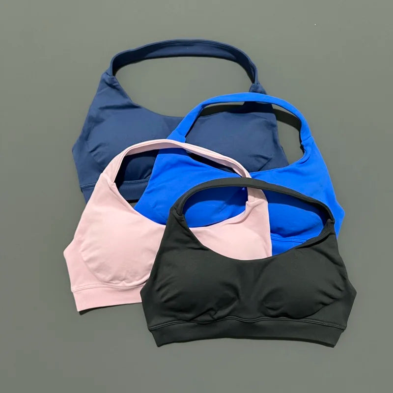 Four sports bras in blue, pink, and black on a gray background