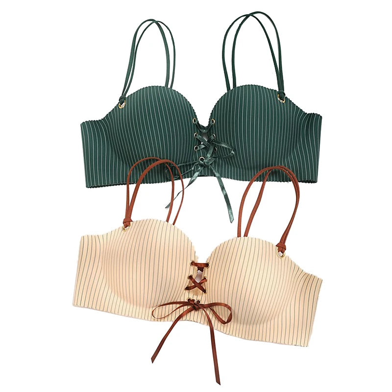 Two strappy lace-up bustier-style bras shown on a plain white background, one in dark green with thin white vertical stripes and one in light beige with thin white vertical stripes.