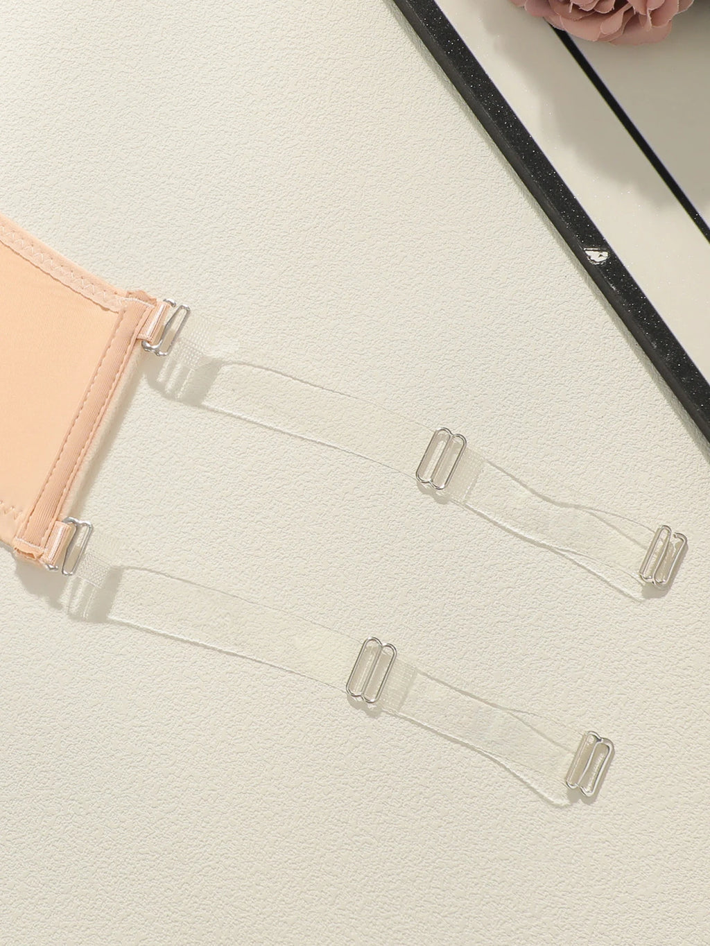 Clear plastic hangers on a light gray surface with a black ironing board corner.