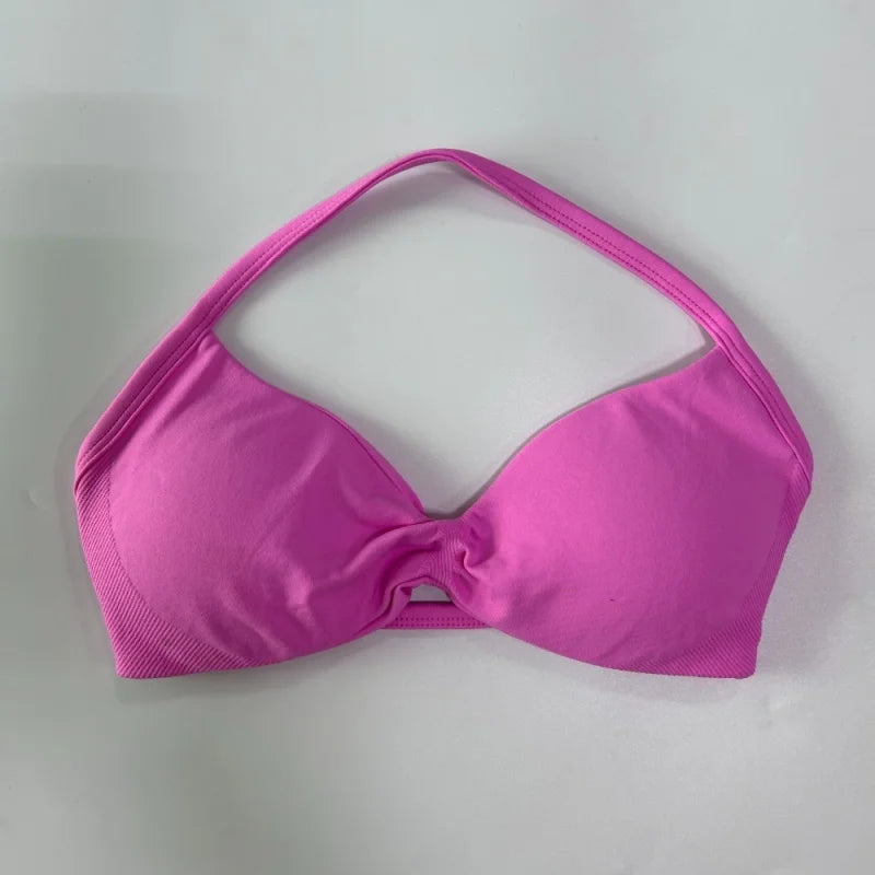A bright pink bikini top with a halter-style strap design and a front twist detail, laid flat on a light gray background.