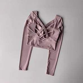 Pink athletic outfit with long sleeves and a crop top on a gray background