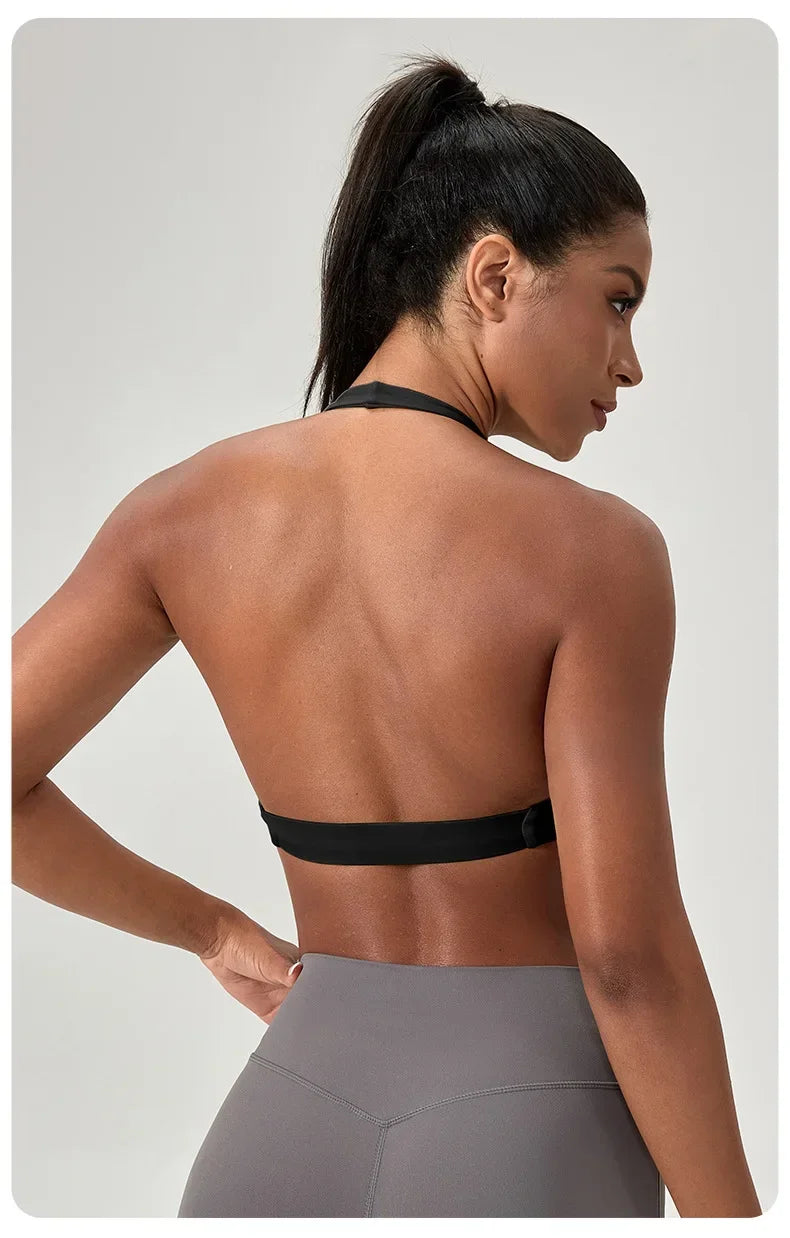 Woman wearing a black sports bra and gray leggings on a light gray background
