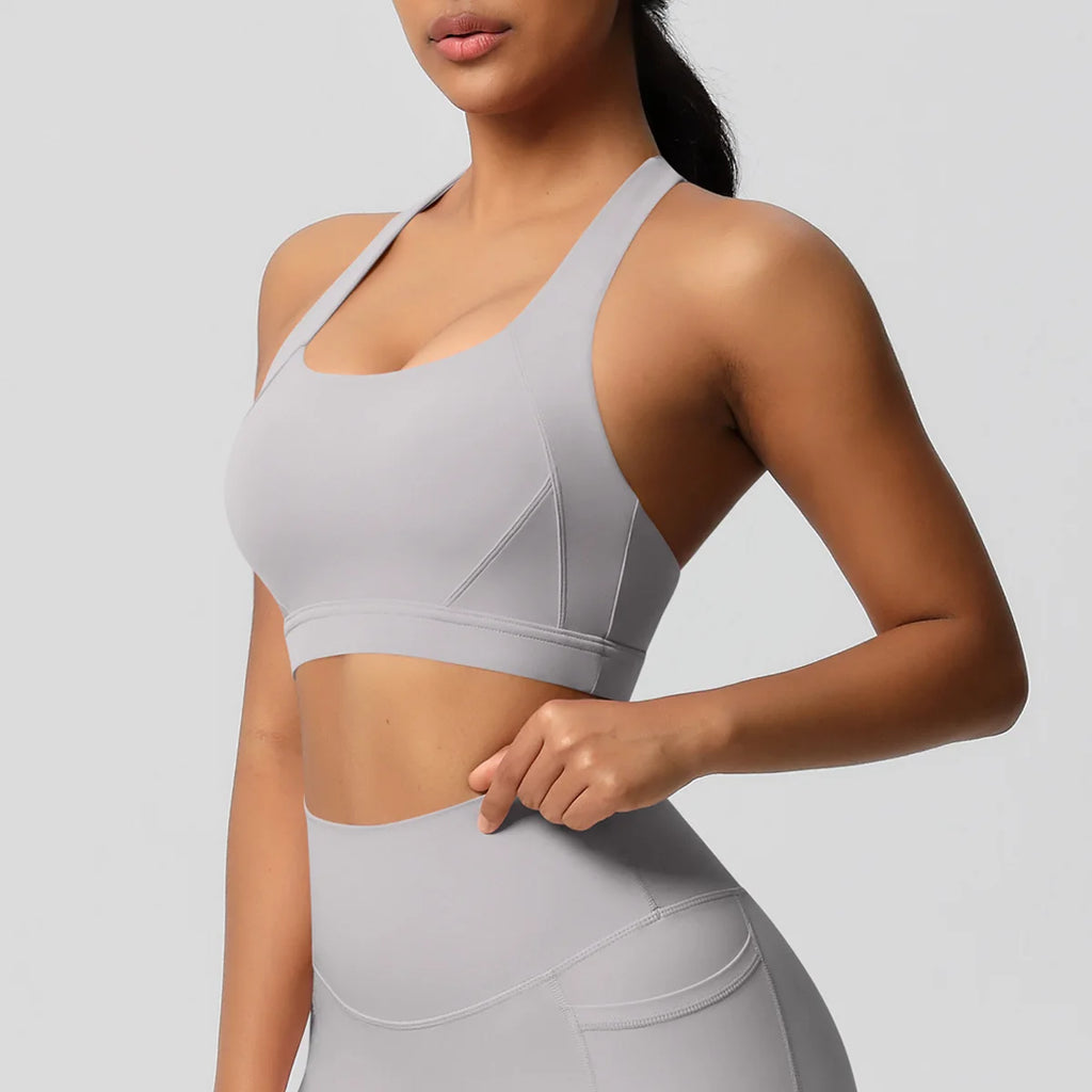 Woman wearing a gray sports bra and leggings on a light gray background