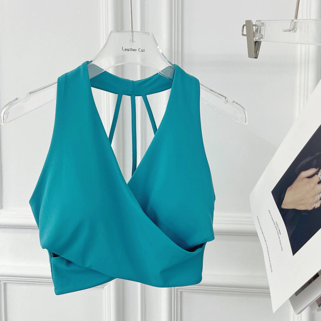 Teal top on a hanger against a white wall with a magazine in the background.