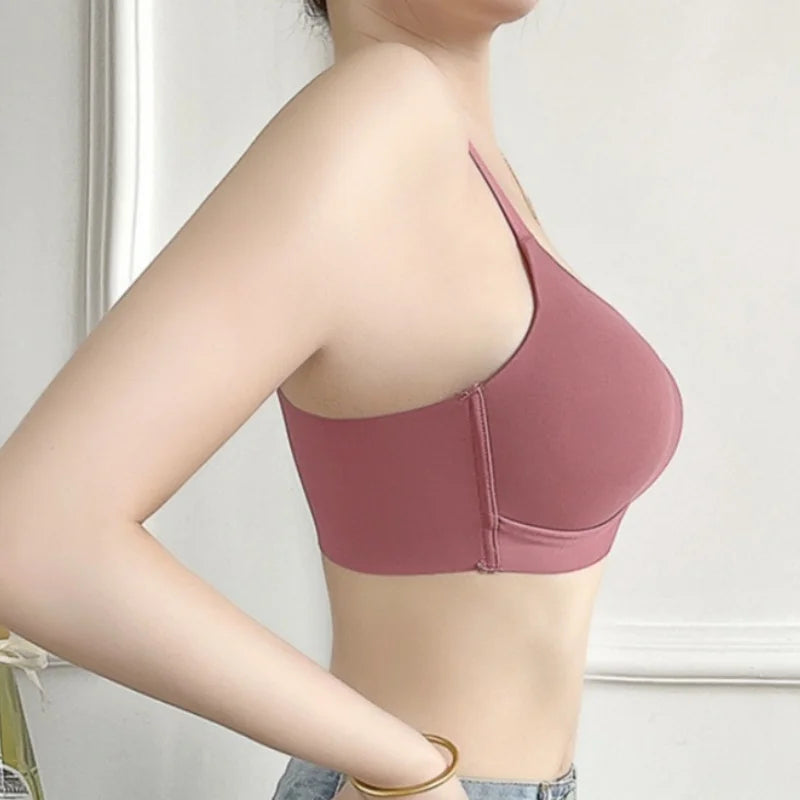 A woman wearing a dusty rose wireless bralette with a center gore and underwire support, shown from a side profile against a light-colored indoor background.