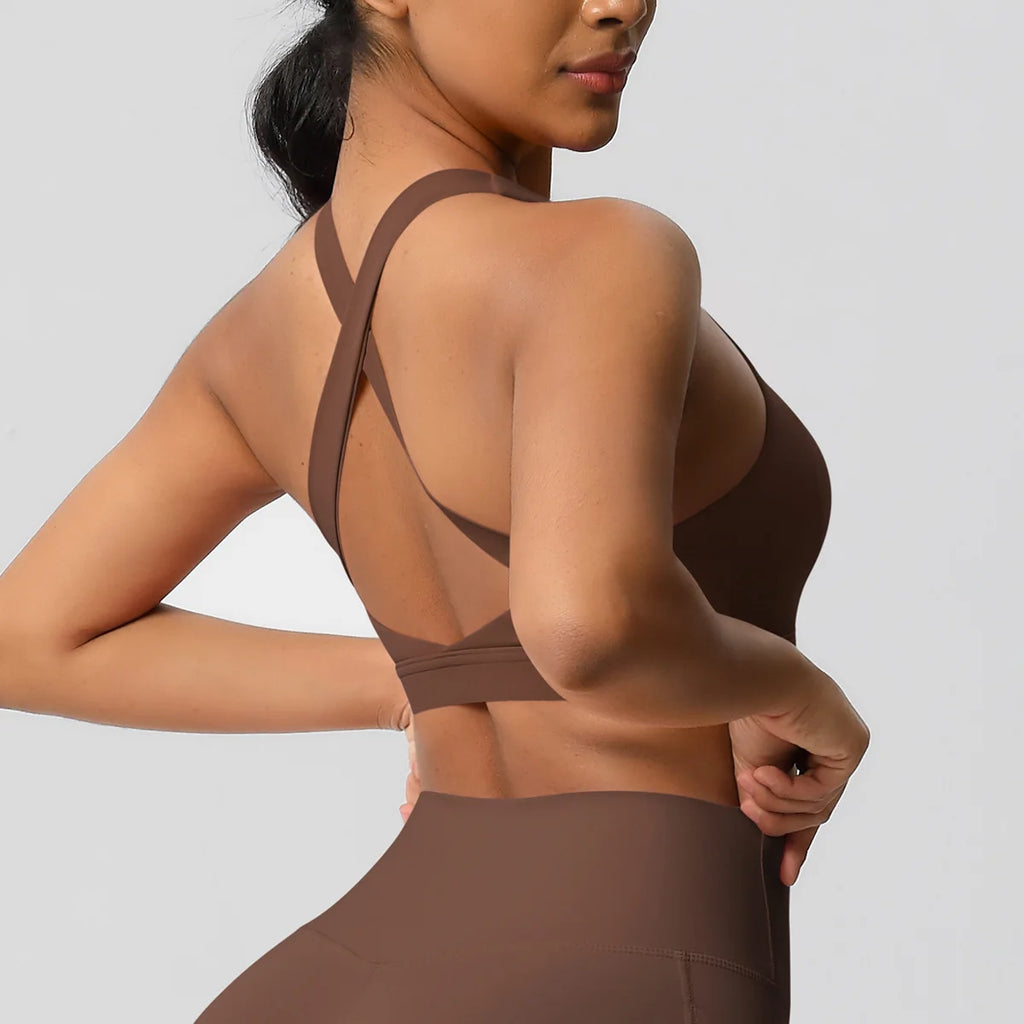 Woman wearing a brown sports bra and leggings on a gray background