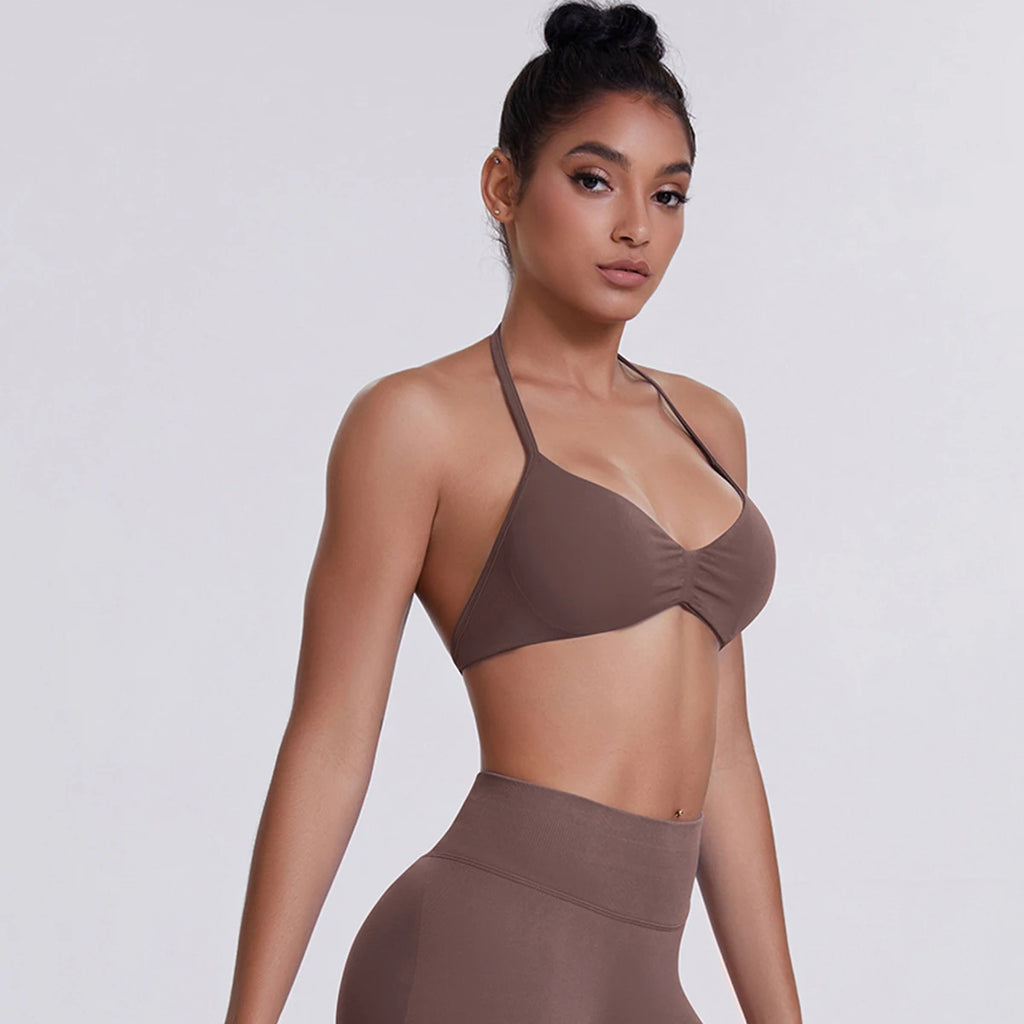 Woman wearing a brown sports bra and leggings on a light gray background