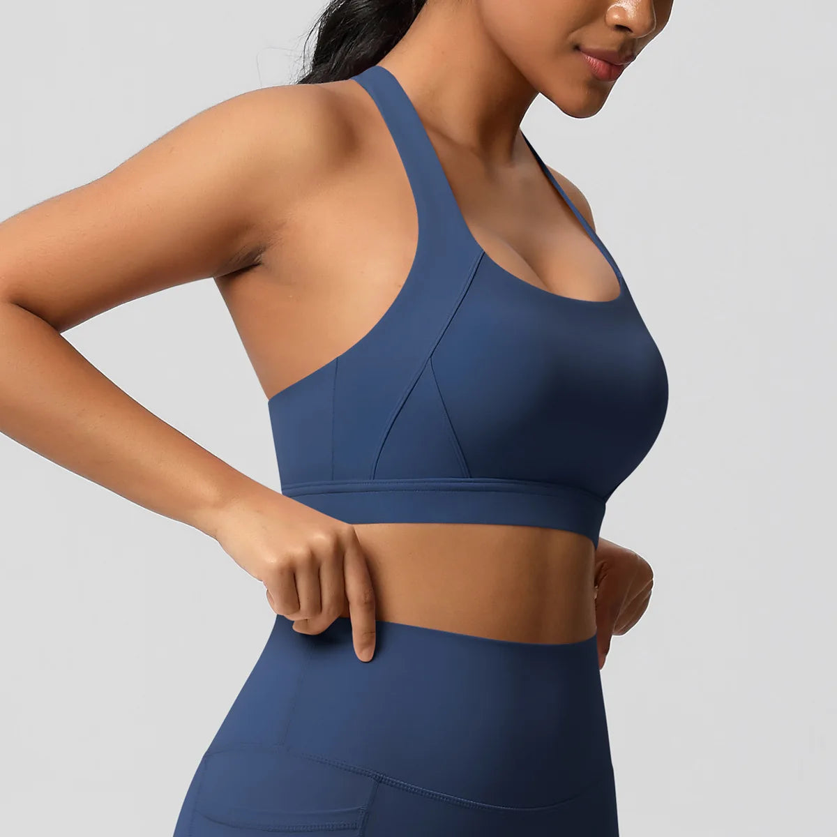 Woman wearing a blue sports bra and leggings on a gray background