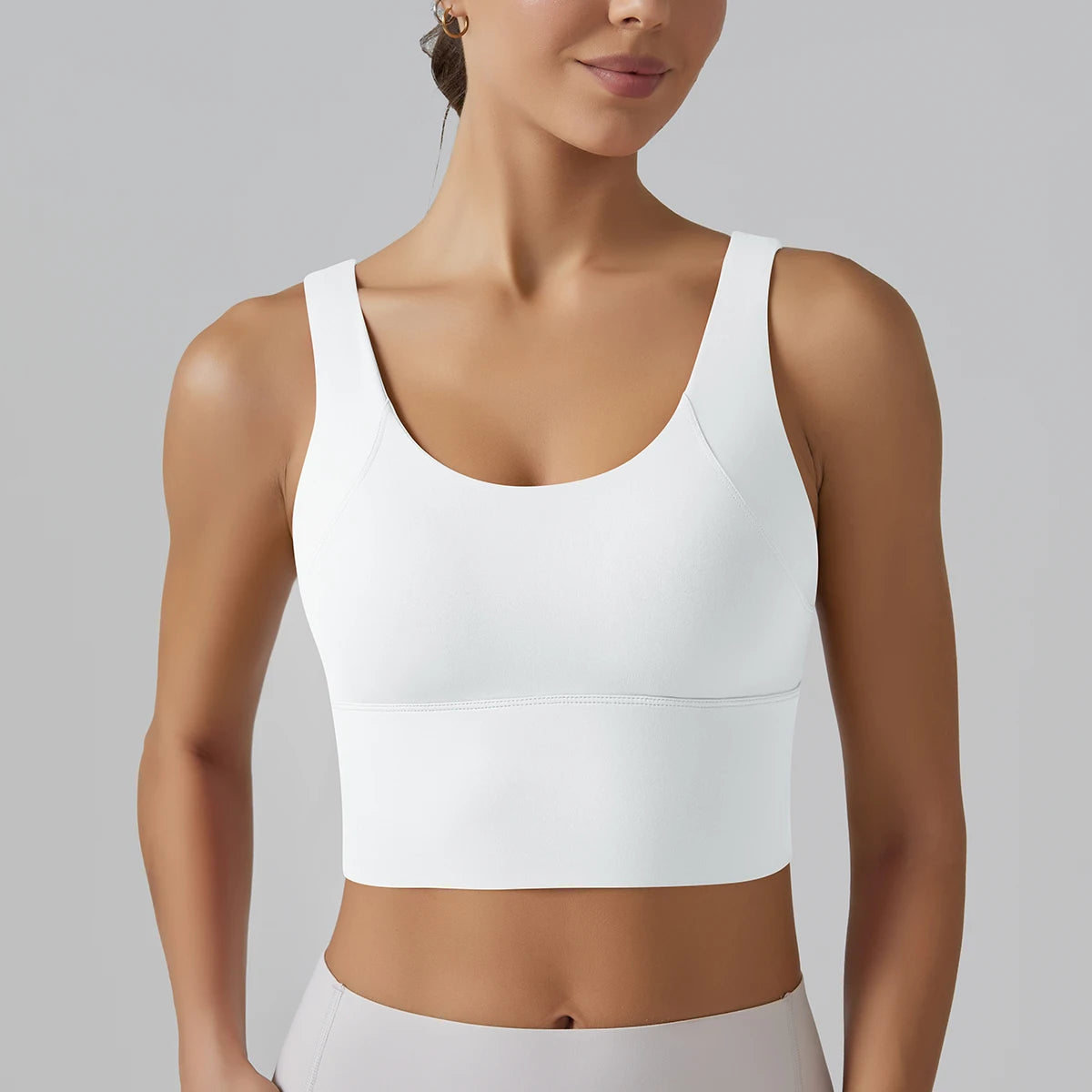 Woman wearing a white sports bra against a gray background