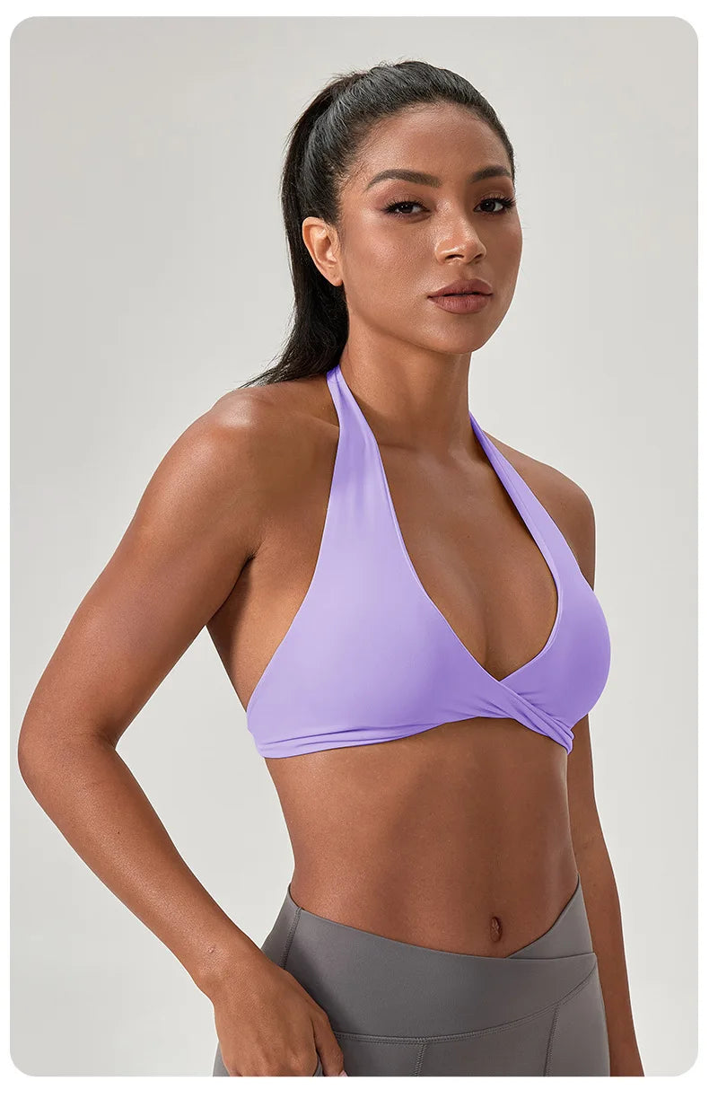 Woman wearing a purple sports bra and gray leggings on a light gray background