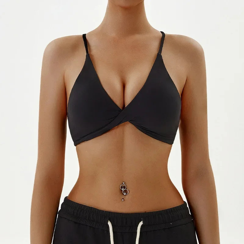 Person wearing a black sports bra and black shorts on a white background