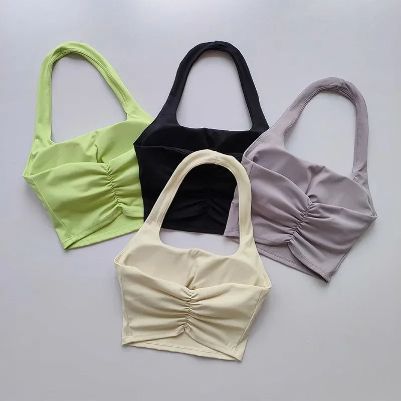 Four crop tops in green, black, beige, and purple on a light gray background
