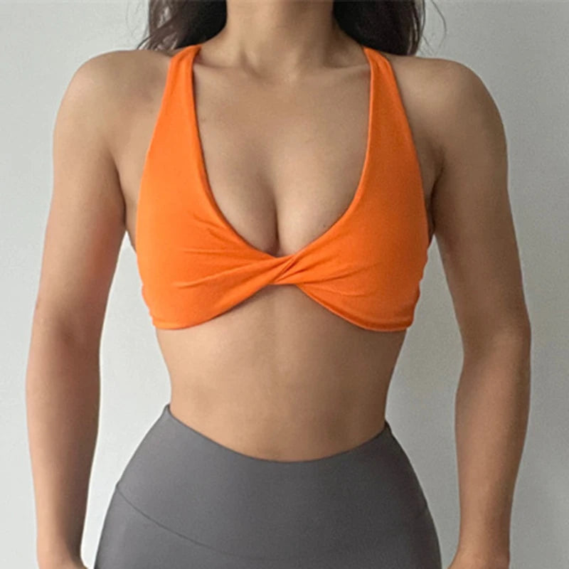 Person wearing an orange sports bra and gray leggings on a plain background