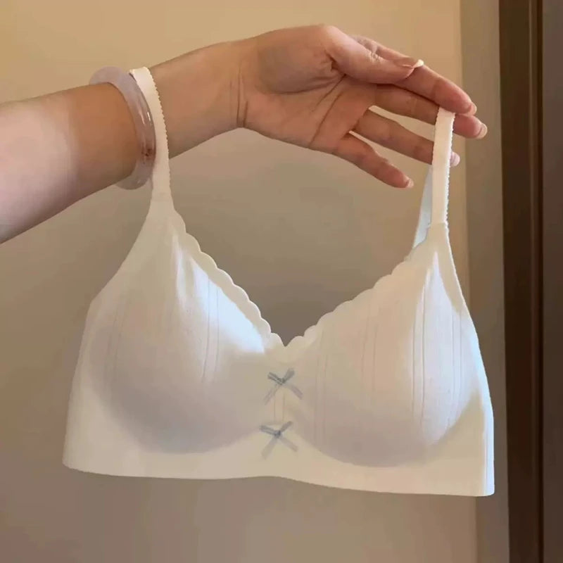 White bra held by a hand against a neutral background