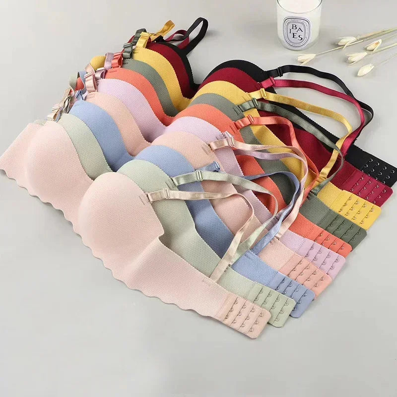 Collection of colorful bras arranged on a light gray surface with a candle and decorative elements in the background.
