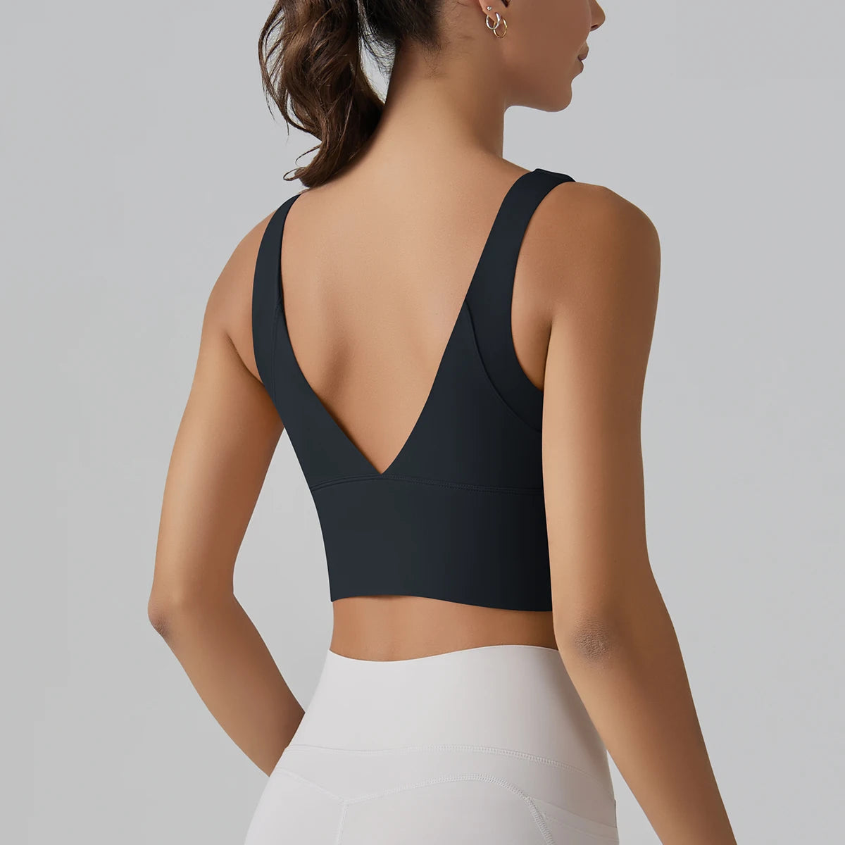 Person wearing a black sports bra and white pants on a gray background