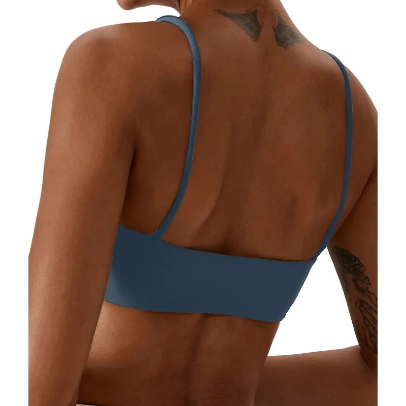 Rear view of a woman wearing a solid slate blue sports bra against a plain white background.